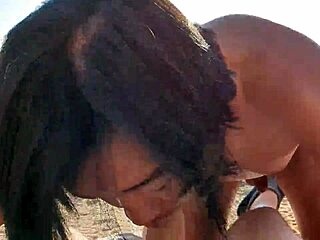 A nude Asian man gives a deepthroat blowjob to a white man on a Mediterranean beach